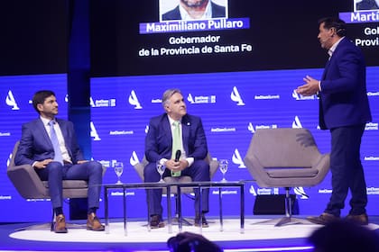Los gobernadores Pullaro y Llaryora en el AmCham Summit 2025, junto al moderador Ariel Maciel
