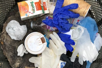 Los guantes y demás suministros médicos se mezclan con los vasos de café en los tachos de Manhattan