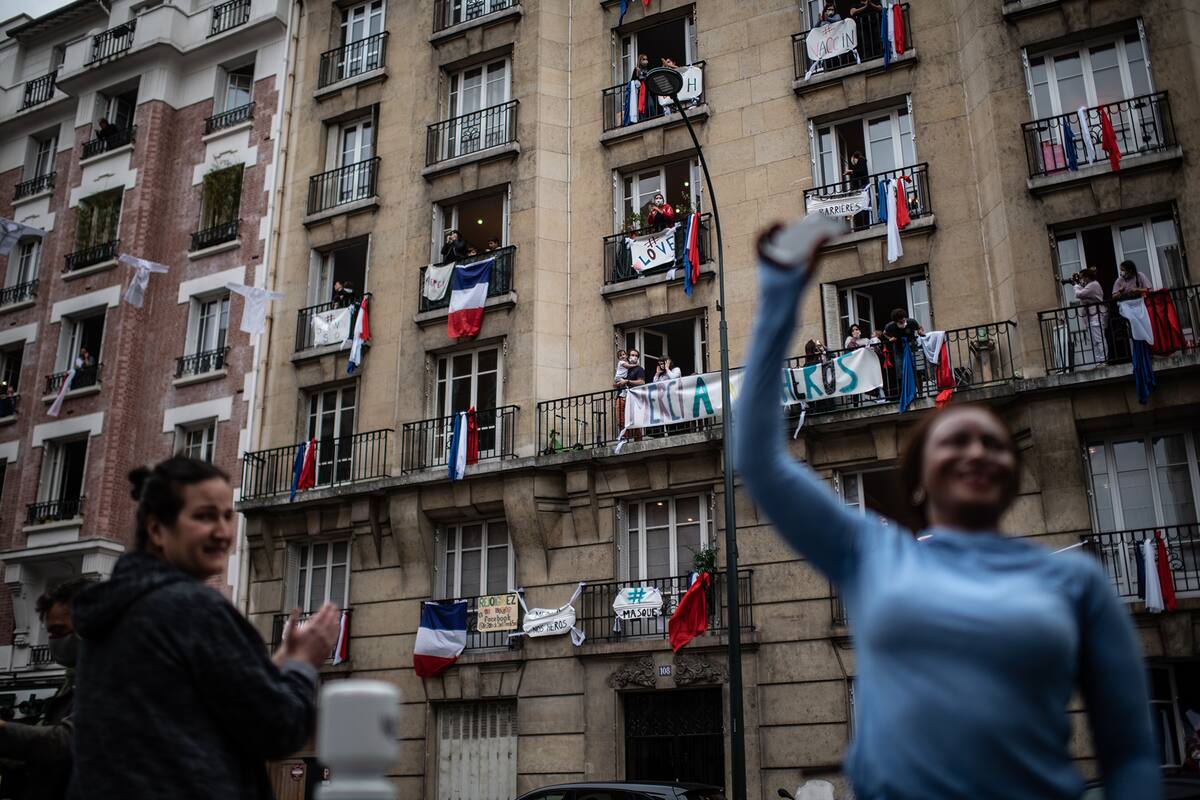 Los habitantes aplauden a las 20:00 horas a los empleados de la salud en Saint-Mande, un suburbio de París, el 4 de mayo de 2020 durante el día 49 de un encierro en Francia destinado a frenar la propagación del nuevo coronavirus