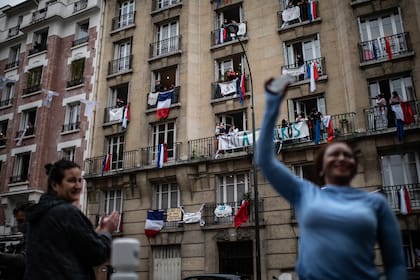 Los habitantes aplauden a las 20:00 horas a los empleados de la salud en Saint-Mande, un suburbio de París, el 4 de mayo de 2020 durante el día 49 de un encierro en Francia destinado a frenar la propagación del nuevo coronavirus