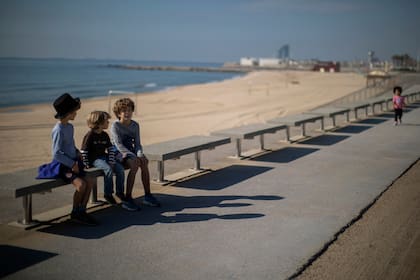 Los hermanos Pau, 4, Jan 7 y Leo, 9, se sientan cerca de la playa, donde la policía prohíbe el acceso, en Barcelona, España