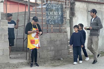 Los hermanos van junto a su papá al comedor Gauchito Gil a retirar la comida para la cena
