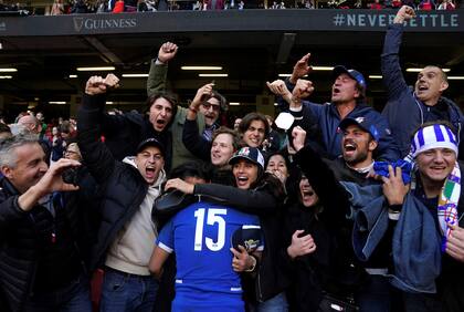 Los hinchas italianos abrazan a Ange Capuozzo tras la última jugada del partido, que le permitió a Italia derrotar a Gales como visitante
