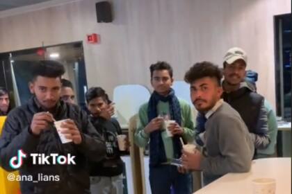 Los hombres indios en el local de comida rápida observando a la joven occidental