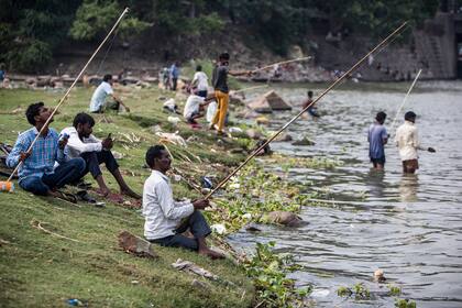 Los hombres pescan a lo largo de las orillas del río Yamuna en Nueva Delhi, India, el 25 de junio de 2020