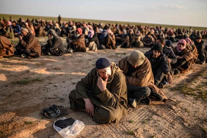 Los hombres sospechosos de ser combatientes de Estado Islámico (EI) esperan que los miembros de las Fuerzas Democráticas Sirias (SDF) lideradas por los kurdos los registren