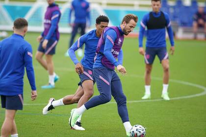 Los ingleses Harry Kane y Jude Bellingham disputan un balón durante un entrenamiento en St George's Park, Burton upon Trent, Inglaterra, sábado 10 de julio de 2021. Inglaterra se prepara para enfrentar a Italia en la final de la Eurocopa, el domingo en Wembley. (AP Foto/Dave Thompson)