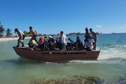 Los inmigrantes cubanos bajan a toda velocidad de la embarcación para tocar tierra firme y huir de la playa