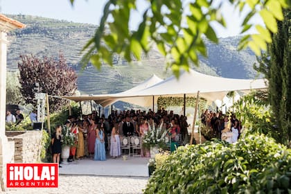 Los invitados esperan la llegada de los novios protegidos del sol. Al fondo, puede verse el altar con un gran arco de flores blancas donde se celebró la boda.