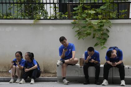 Los jóvenes miran sus celulares en la calle en Pekín, el jueves 3 de agosto de 2023.