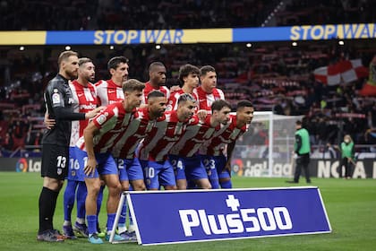 Los jugadores de Atlético de Madrid posan para la foto mientras de fondo los letreros electrónicos del estadio Metropolitano piden "detener la guerra" en azul y amarillo, en apoyo a Ucrania.