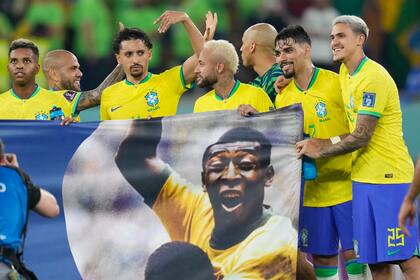 Los jugadores de la selección brasileña muestran una pancarta con la imagen de la leyenda del fútbol, Pelé, --quien continuaba hospitalizado-- al final del partido contra Corea el Sur en los octavos de final de la Copa del Mundo, en el estadio 974, en Doha, Qatar, el lunes 5 de diciembre de 2022. (AP Foto/Andre Penner)