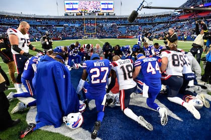 Los jugadores de los Bills de Buffalo y los Patriots de Nueva Inglaterra oran el doming o8 de enero de 2023, tras su partido en Orchard Park, Nueva York (AP Foto/Adrian Kraus)