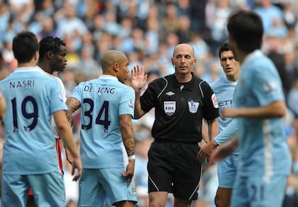 Los jugadores de Manchester City rodean para protestarle al árbitro Mike Dean