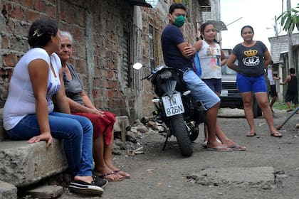 Los lugareños permanecen fuera de sus casas ubicadas en los alrededores del cementerio Pascuales, al norte de Guayaquil, Ecuador, el 18 de mayo de 2020