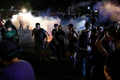 Los manifestantes corren a cubrirse mientras la policía dispara gases lacrimógenos en un esfuerzo por dispersar a la multitud fuera del Palacio de Justicia del Condado durante las manifestaciones contra el tiroteo de Jacob Blake en Kenosha, Wisconsin, el 25 de agosto de 2020