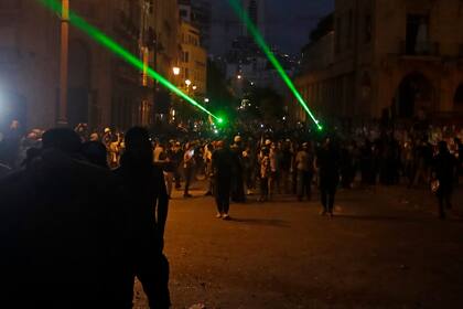 Los manifestantes libaneses utilizan punteros láser contra las fuerzas de seguridad en medio de enfrentamientos cerca de una calle de acceso al parlamento en el centro de Beirut el 9 de agosto de 2020