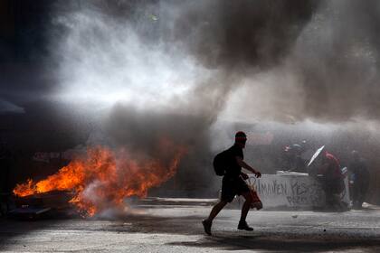 Los manifestantes son rociados con un cañón de agua por la policía antidisturbios durante los enfrentamientos que estallaron durante la conmemoración del primer aniversario del levantamiento social en Chile, en Santiago, el 18 de octubre de 2020