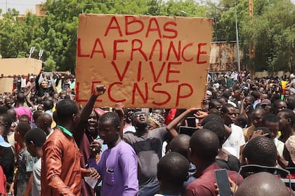 Los manifestantes sostienen un letrero que dice "Abajo con Francia, viva el CNSP" durante una marcha en apoyo a los conspiradores del golpe de estado el 30 de julio de 2023.