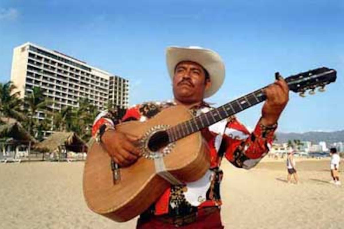 Los mariachis se asolean en las arenas de Acapulco para alegrar la estada de sus visitantes, que llegan a tres millones