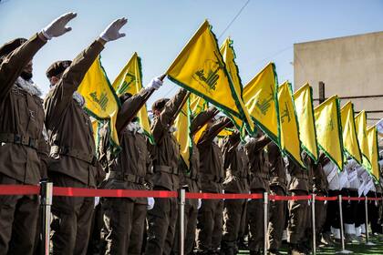 Los miembros de Hezbollah saludan e izan las banderas amarillas del grupo durante el funeral de sus camaradas caídos Ismail Baz y Mohamad Hussein Shohury, que murieron en un ataque israelí, el 17 de abril de 2024.