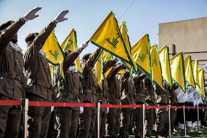Los miembros de Hezbollah saludan e izan las banderas amarillas del grupo durante el funeral de sus camaradas caídos Ismail Baz y Mohamad Hussein Shohury, que murieron en un ataque israelí, el 17 de abril de 2024.