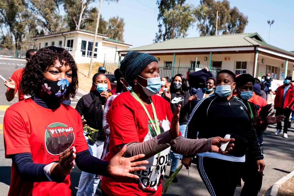 Los miembros del Sindicato Nacional de Trabajadores de la Educación, la Salud y Afines de Sudáfrica (NEHAWU) protestan frente al Servicio Nacional de Laboratorios de Salud (NHLS) en Johannesburgo el 21 de agosto de 2020, para exigir un mejor equipo de protección contra el coronavirus COVID-19, aumen
