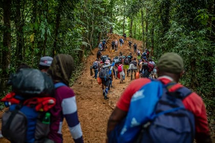 Los migrantes, cargados con sus pertenencias que se vieron obligados a dejar caer a medida que la caminata se hacía más difícil, cruzan el Tapón del Darién. (Federico Rios/The New York Times)