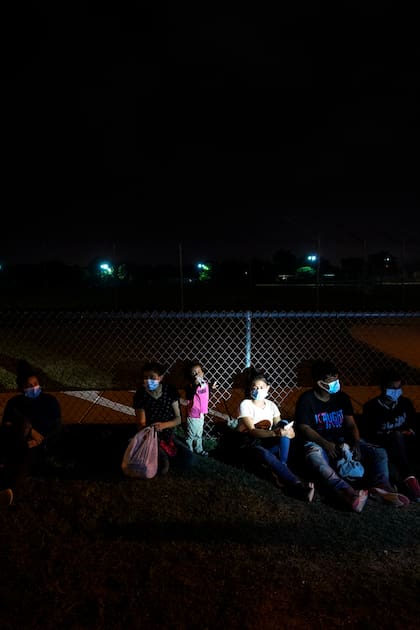Los migrantes descansan después de entregarse a las autoridades al cruzar la frontera entre Estados Unidos y México