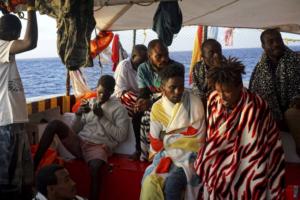 Los migrantes se sientan a bordo del barco humanitario español Open Arms cuando llega cerca de la costa de Lampedusa en el mar Mediterráneo, el jueves 15 de agosto de 2019