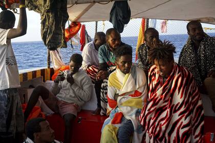 Los migrantes se sientan a bordo del barco humanitario español Open Arms cuando llega cerca de la costa de Lampedusa en el mar Mediterráneo, el jueves 15 de agosto de 2019