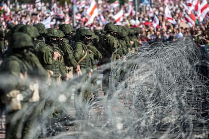 Los militares bielorrusos se paran detrás de una cerca de alambre de púas durante una manifestación de partidarios de la oposición que protestan contra los resultados de las elecciones presidenciales en disputa en Minsk el 30 de agosto de 2020