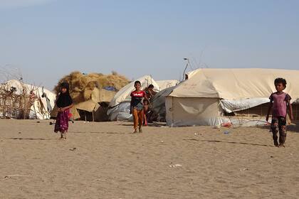 Los niños caminan frente a las tiendas de campaña en un campamento de personas desplazadas en el distrito de Khokha de la provincia occidental de Yede, en Yemen, el 6 de mayo de 2020