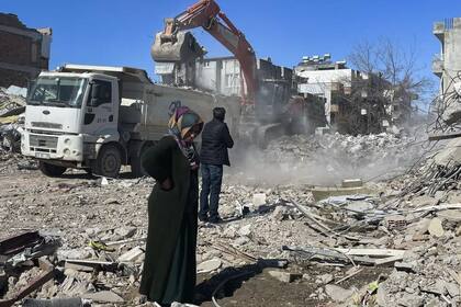 Los padres de Taha Erdem, la madre Zeliha Erdem, a la izquierda, y el padre Ali Erdem, junto a los escombros del edificio donde Tahan quedó atrapado tras el terremoto del 6 de febrero, en Adiyaman, Turquía, el viernes 17 de febrero de 2023. Taha Erdem, residente de Adiyaman, en el sureste de Turquía, es uno de los cientos de supervivientes sacados de edificios derrumbados tras el fuerte terremoto del 6 de febrero. Erdem, de 17 años, se grabó a sí mismo con su teléfono mientras estaba atascado y atrapado entre el hormigón en lo que pensó que serían sus últimas palabras. (AP Photo/Mehmet Mucahit Ceylan)