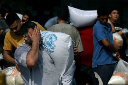 Los palestinos recogen bolsas de legumbres secas en un centro de suministro de ayuda gestionado por la ONU y distribuyen alimentos a los palestinos locales y a las personas desplazadas