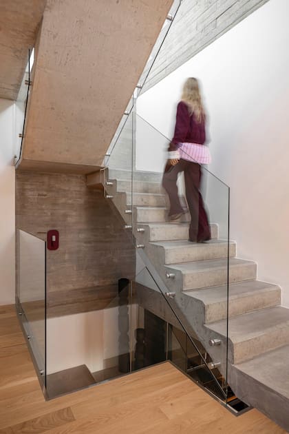 Los paneles de vidrio acompañan todo el recorrido de la escalera, unificando el estilo sin interrumpir el paso de la luz.