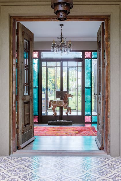 Los paños turquesa y fucsia convierten el acceso en una verdadera escena de bienvenida en la casa de Cecilia Astigarraga proyectada por Estudio A&T Arqs.