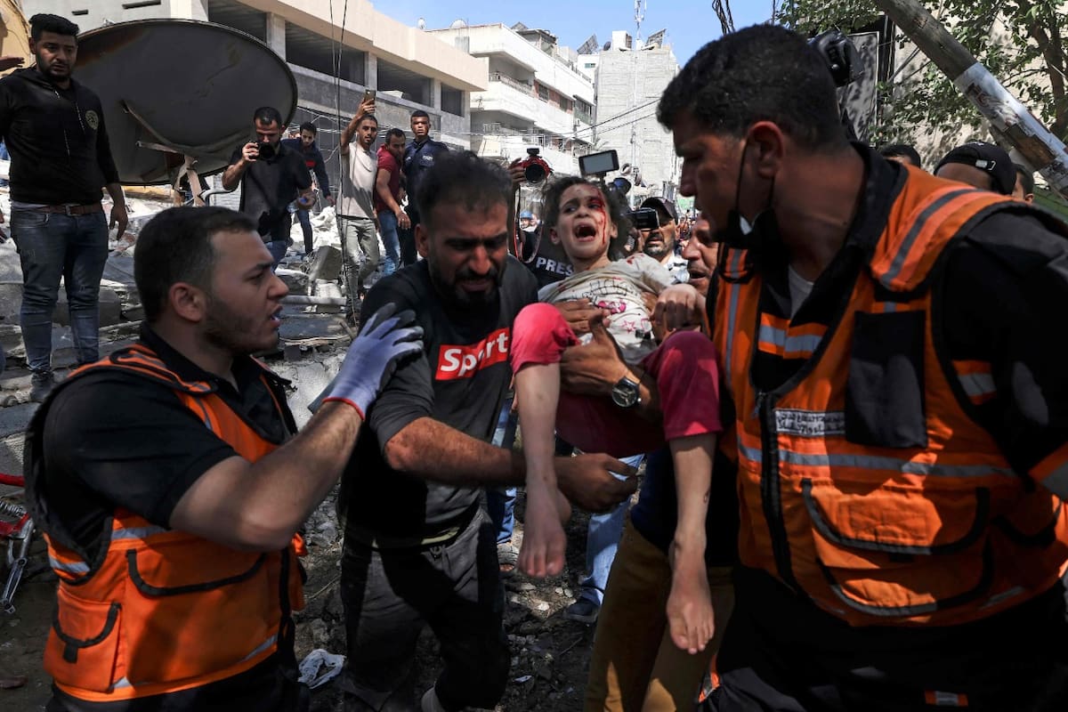 Los paramédicos palestinos evacuan a una niña de los escombros de un edificio destruido en el distrito residencial Rimal de la ciudad de Gaza, el 16 de mayo de 2021, luego del bombardeo masivo israelí en el enclave controlado por Hamas