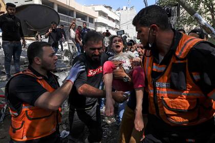 Los paramédicos palestinos evacuan a una niña de los escombros de un edificio destruido en el distrito residencial Rimal de la ciudad de Gaza, el 16 de mayo de 2021, luego del bombardeo masivo israelí en el enclave controlado por Hamas
