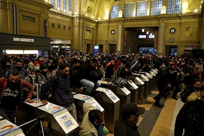 Los pasajeros saltan los molinetes para llegar a las formaciones luego de un día de caos en Constitución