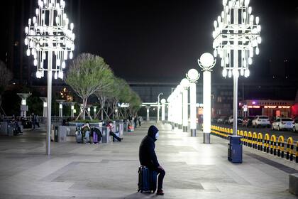 Los pasajeros usan barbijos mientras forman una fila en la estación de tren Wuhan Wuchang, a principios del 8 de abril de 2020, mientras se preparan para abandonar la ciudad en la provincia central de Hubei en China