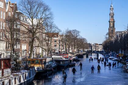 Los patinadores se reúnen sobre hielo en los canales de Prinsengracht, Ámsterdam, el 13 de febrero de 2021, cuando las autoridades municipales pidieron a los residentes que patinen en sus propios vecindarios para evitar la acumulación de multitudes y así intentar detener la propagación del coronavirus