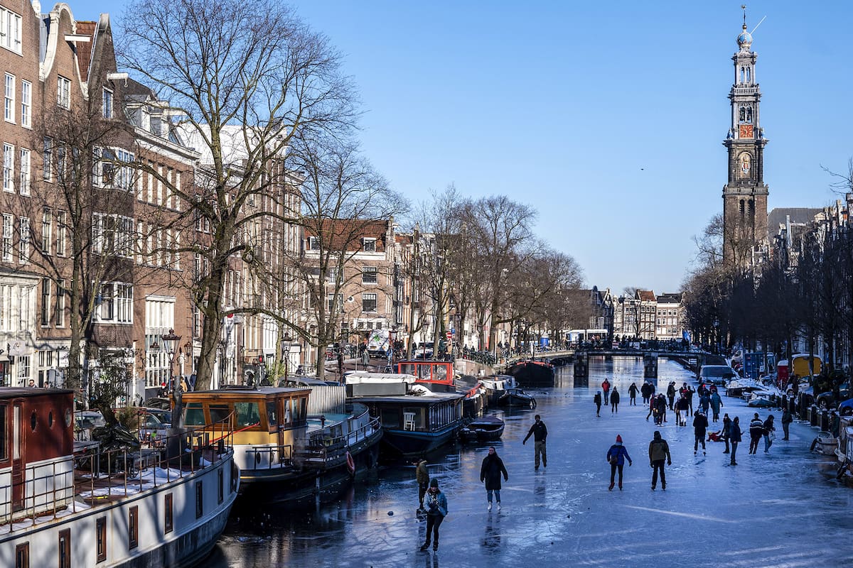 Los patinadores se reúnen sobre hielo en los canales de Prinsengracht, Ámsterdam, el 13 de febrero de 2021, cuando las autoridades municipales pidieron a los residentes que patinen en sus propios vecindarios para evitar la acumulación de multitudes y así intentar detener la propagación del coronavirus