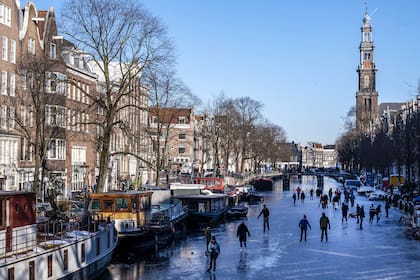 Los patinadores se reúnen sobre hielo en los canales de Prinsengracht, Ámsterdam, el 13 de febrero de 2021, cuando las autoridades municipales pidieron a los residentes que patinen en sus propios vecindarios para evitar la acumulación de multitudes y así intentar detener la propagación del coronavirus
