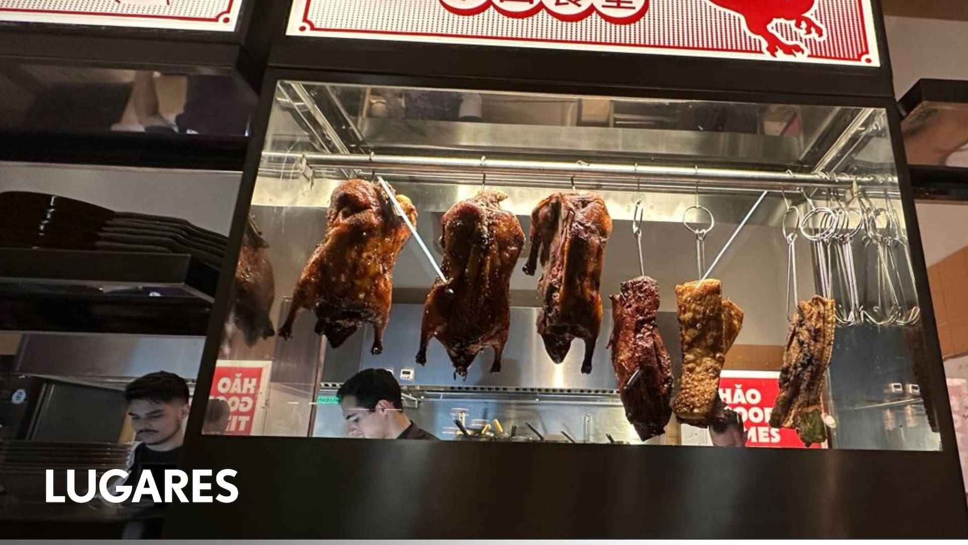 Los patos rostizados se exhiben colgados detrás de un vidrio.