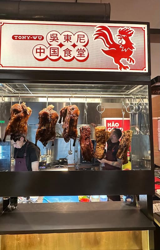 Los patos rostizados se exhiben colgados detrás de un vidrio.