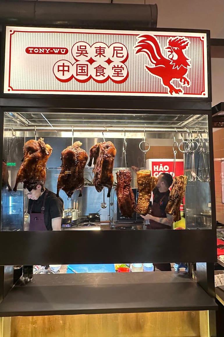 Los patos rostizados se exhiben colgados detrás de un vidrio.