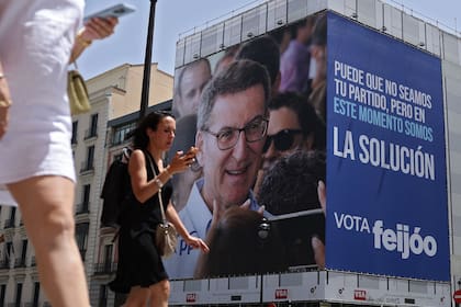 Los peatones pasan junto a un gigantesco cartel electoral que muestra al líder del Partido Popular (PP), partido de oposición de derecha, Alberto Núñez Feijóo, en el centro de Madrid el 19 de julio de 2023, antes de las elecciones generales de España del 23 de julio.