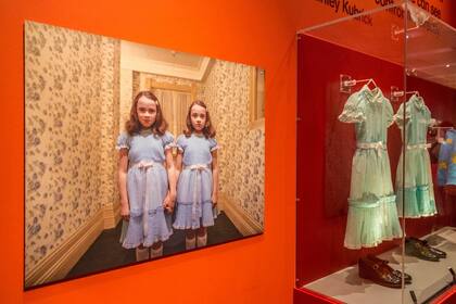 Los pequeños vestidos celestes que usaron las gemelas al final del pasillo en la película El resplandor, entre los objetos de una exposición que recordó a Kubrick, en Londres