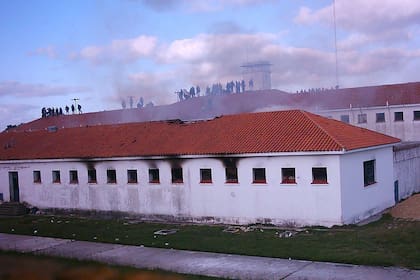 Los presos, en el techo de uno de los edificios del penal de Magdalena, mientras observan el pabellón incendiado